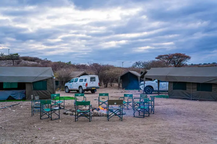 Camp tents and chairs around a fire pit